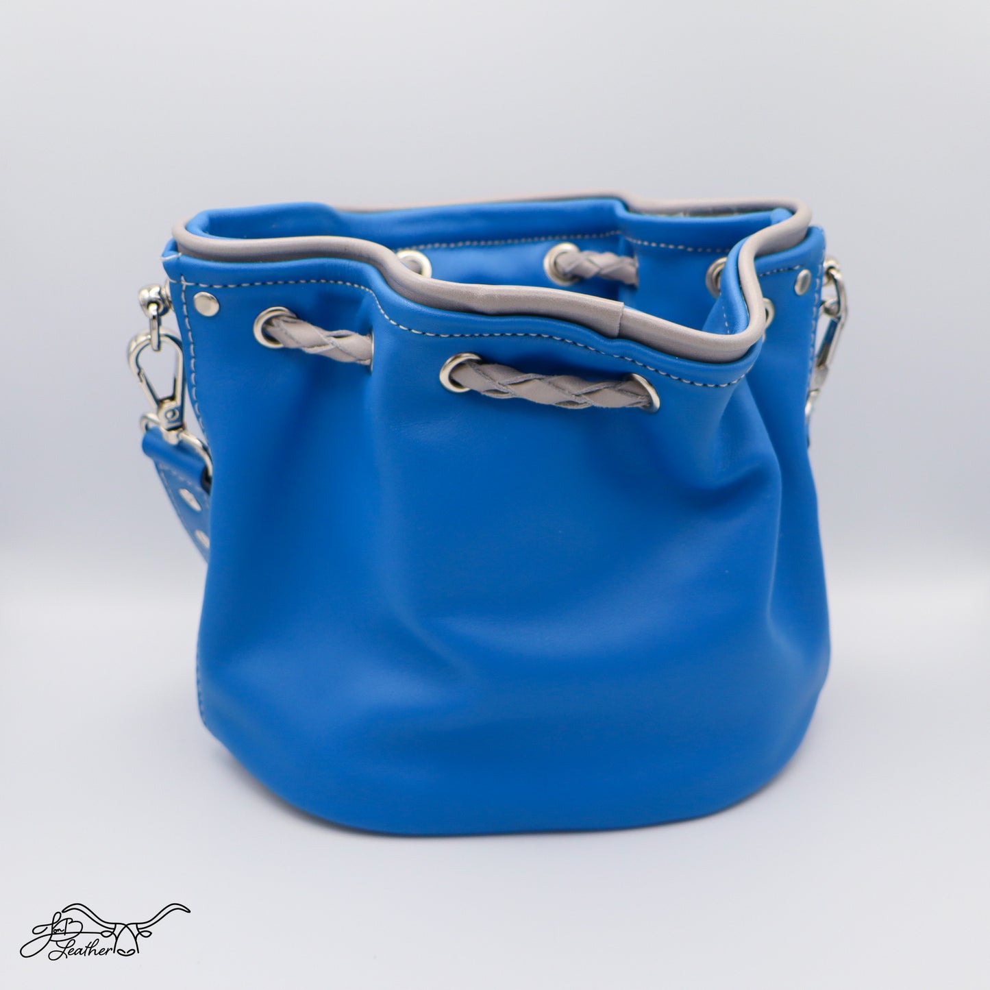 Blue leather crossbody bucket bag with gray drawstring on a white background