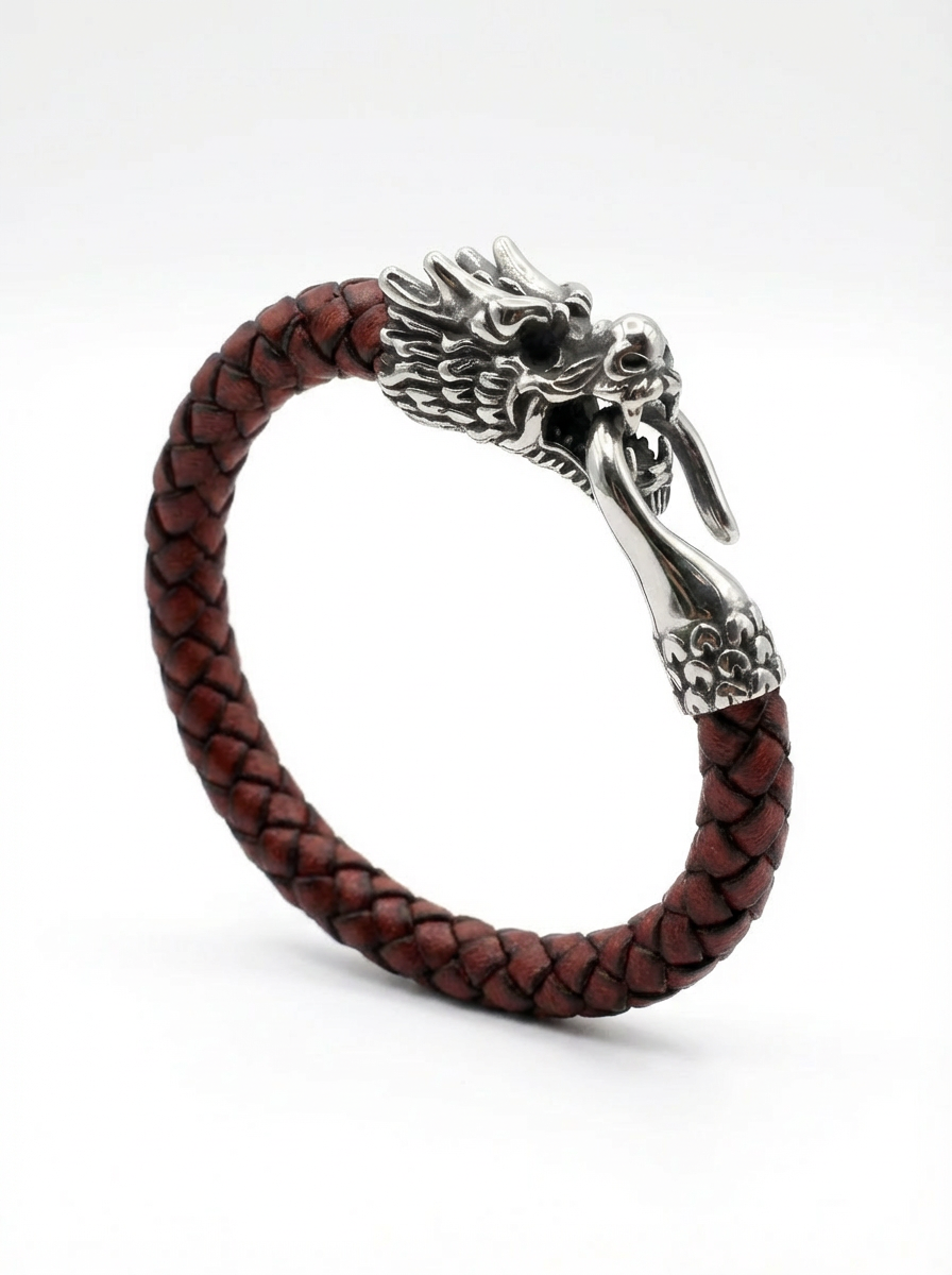 A braided leather bracelet with a detailed silver dragon head clasp, shown on a clean white background.