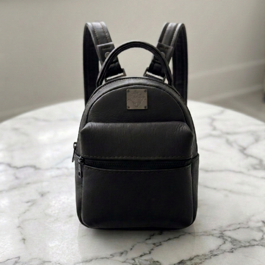 Mini backpack in black full-grain leather on marble table, front view