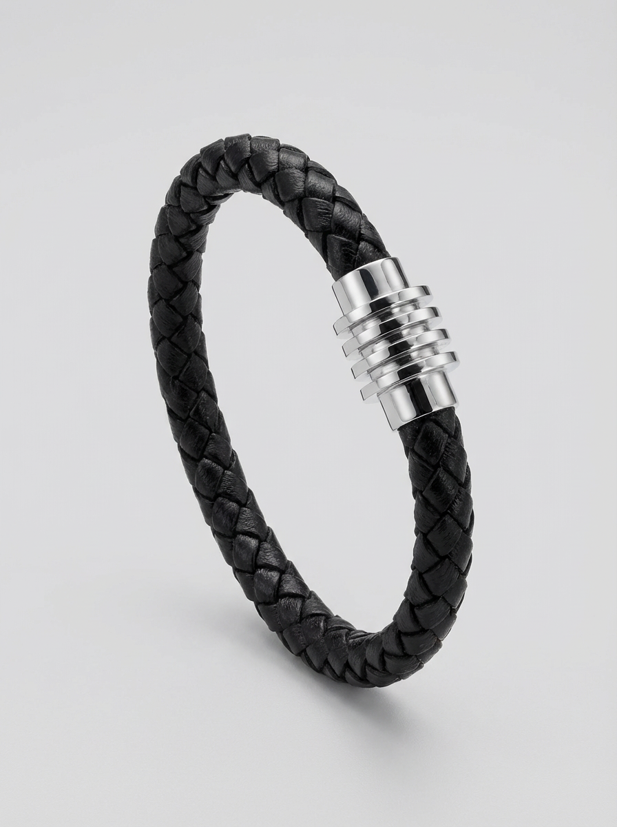 A black braided leather bracelet with a polished silver-toned metal clasp, displayed on a light gray background.