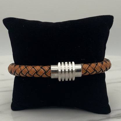 Blonde braided bracelet with a silver clasp on a black cushion against a white background