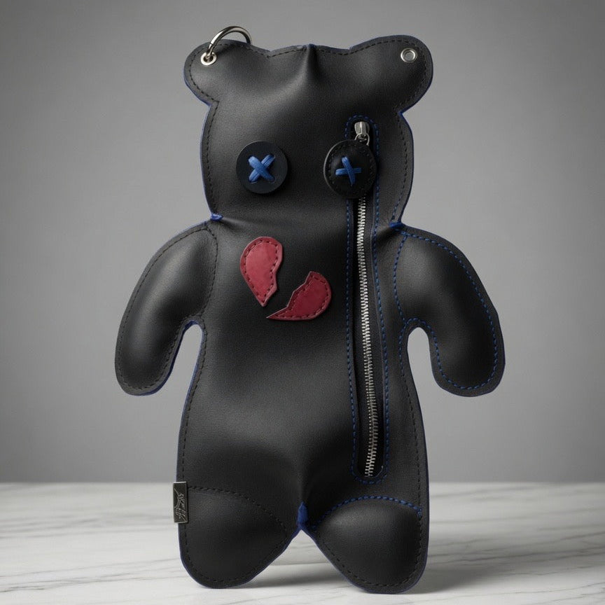 Broken Heart Bear Crossbody in black with blue cross-stitched eyes, red broken-heart detail and front zipper