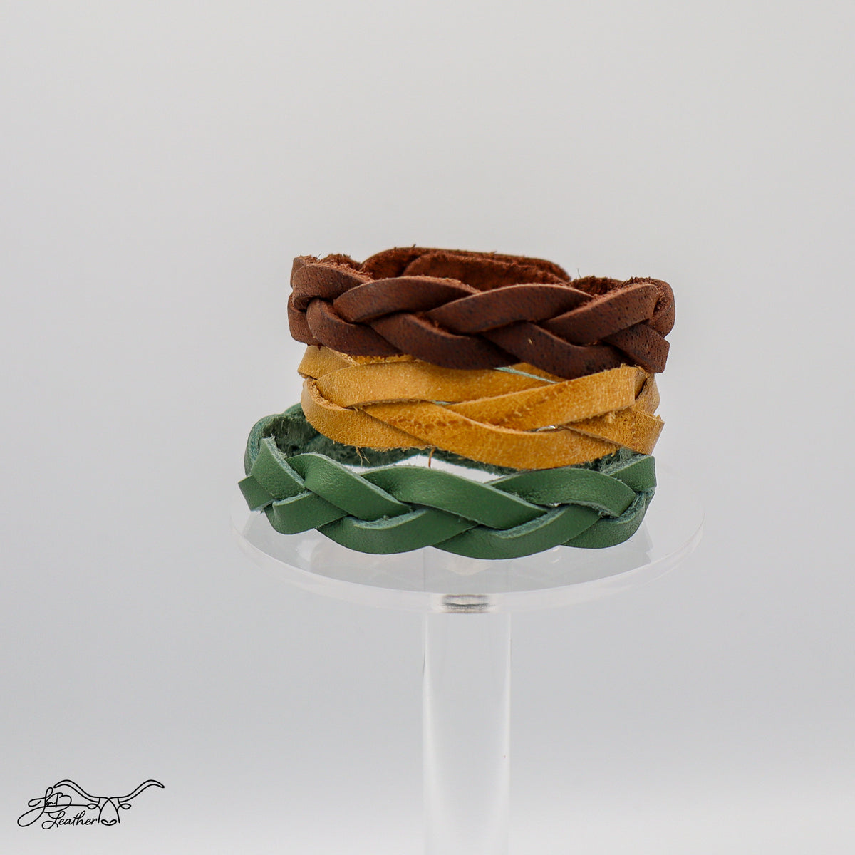 Three "impossible" braided leather bracelets in brown, yellow, and green.