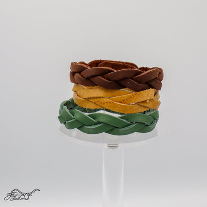 Three "impossible" braided leather bracelets in brown, yellow, and green.
