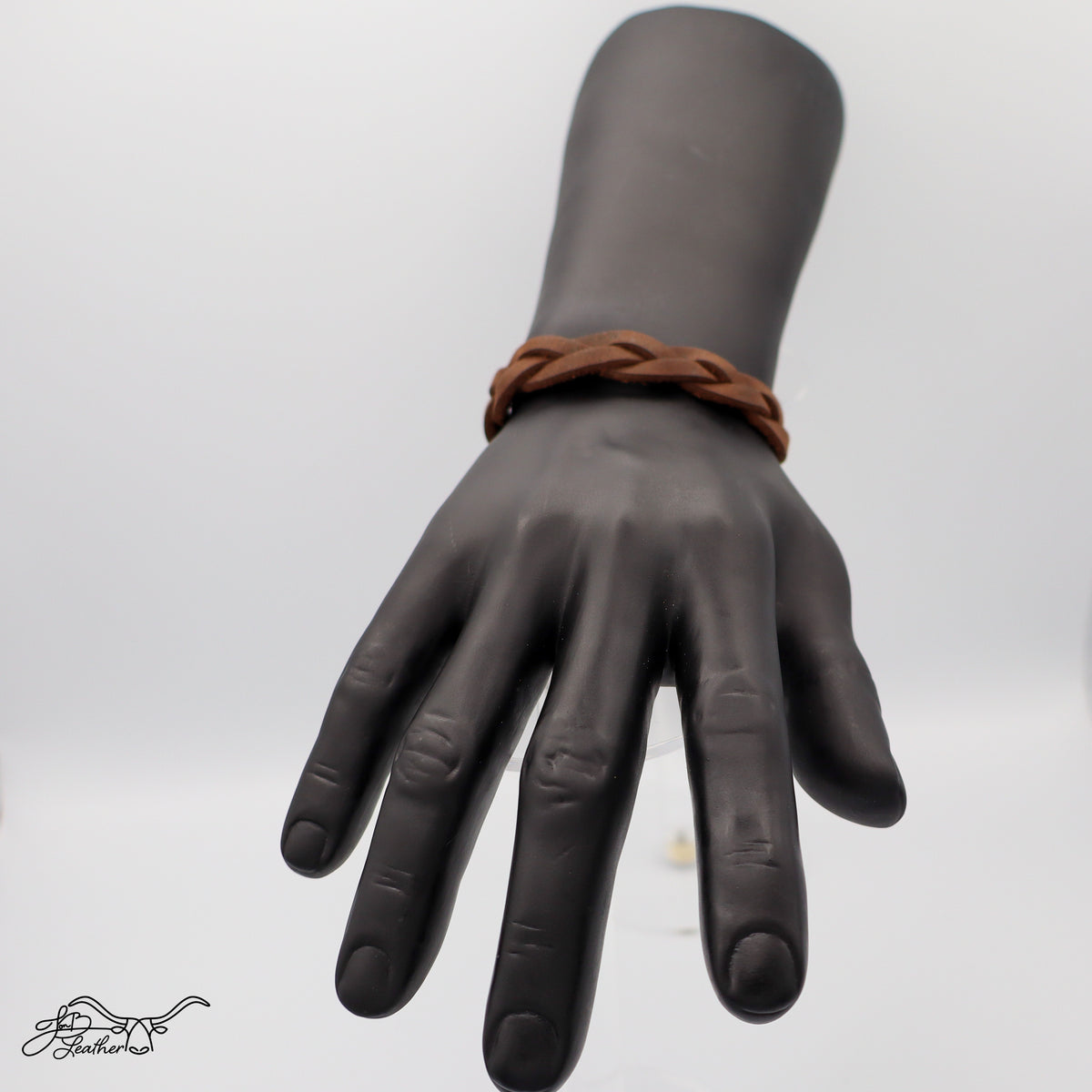 Mannequin hand wearing a brown leather bracelet on a white background
