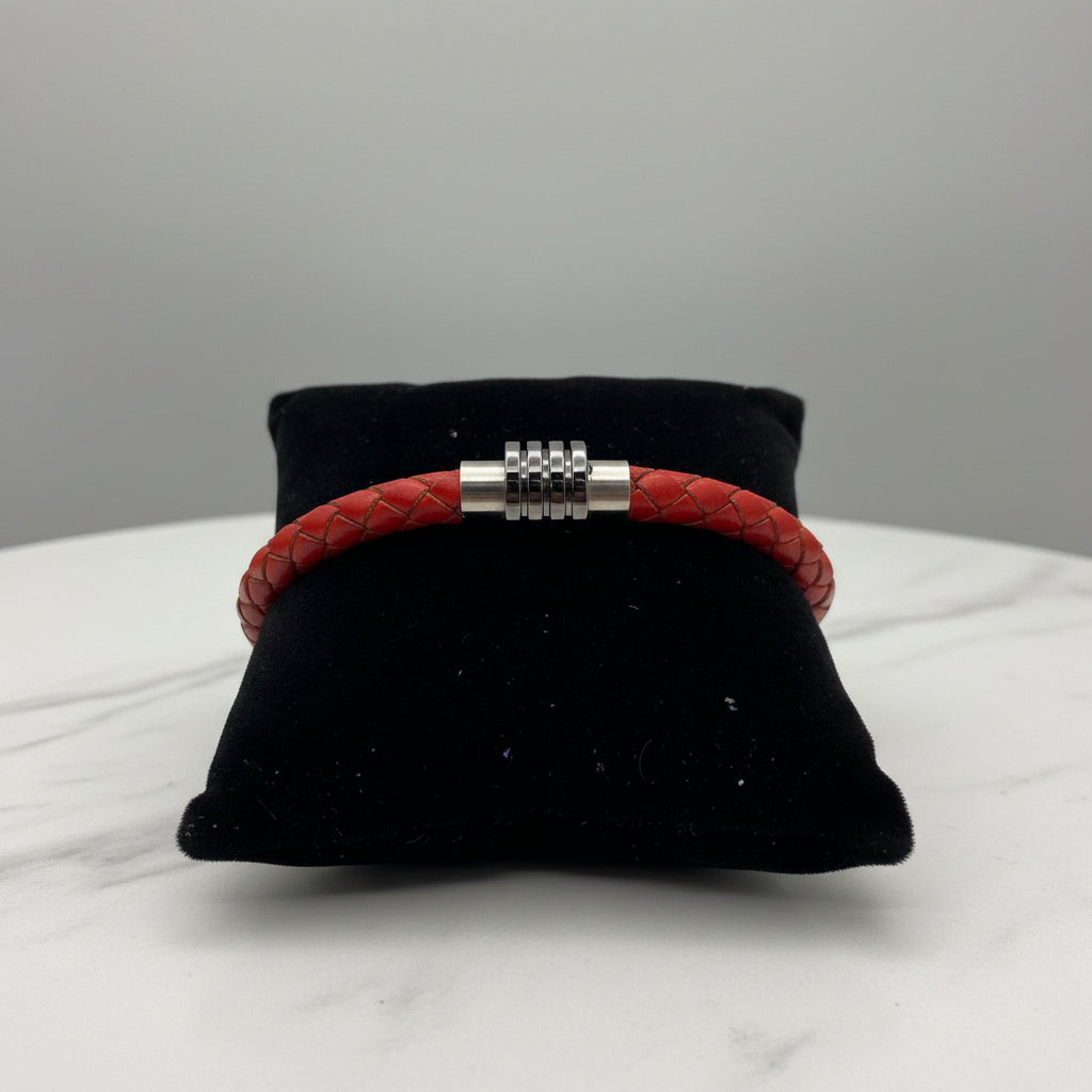 Red braided bracelet with silver Circular Orbit clasp on a black cushion against a gray background